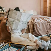 Femeie relaxată cercetând o hartă, în locuinţa ei - Foto: Pexels/Vlada Karpovich