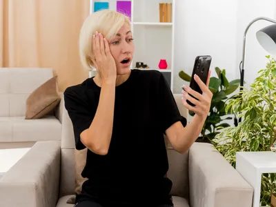 Persoană care se uită speriată la telefon - Foto: Magnific.com (Imagine cu rol ilustrativ)
