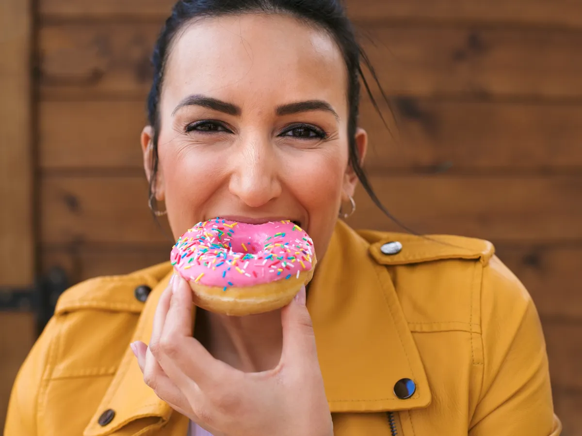 Femeie care mănâncă o gogoașă - Foto: Freepik (Imagine cu rol ilustrativ)