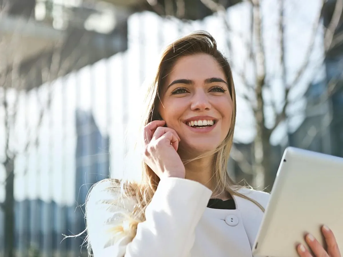 Femeie în blazer alb ţinând în mână un laptop - Foto: Pexels/Andrea Piacquadio