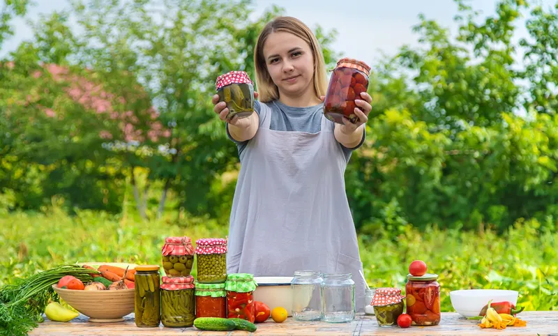 O femeie conservă legume &icirc;n borcane - Foto: Magnific.com (Imagine cu rol ilustrativ)