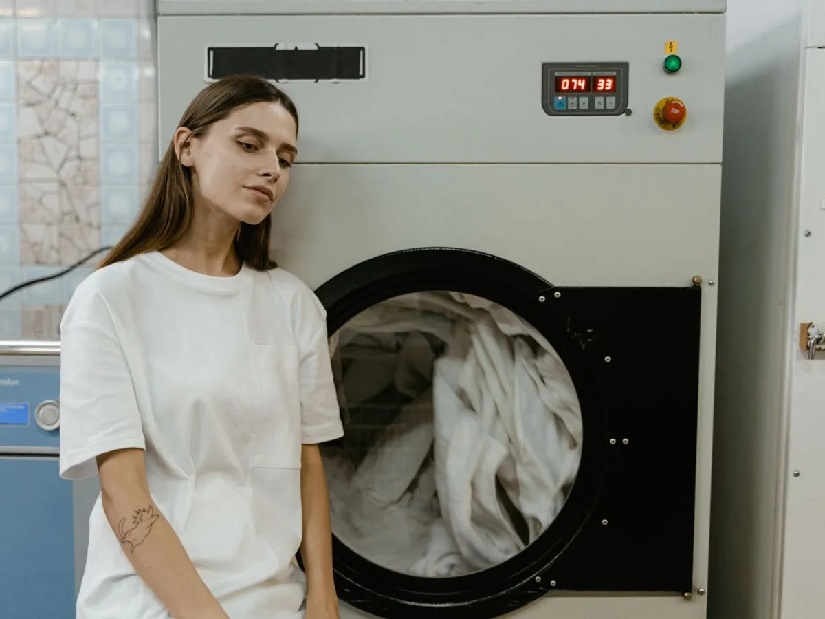 O femeie într-o spălătorie stă lângă o mașină de spălat - Foto: Pexels (Imagine cu rol ilustrativ)