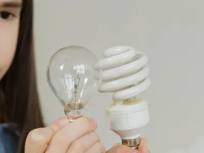 Doi copii ţin în mână două becuri de diferite tipuri - Foto: Pexels/Artem Podrez