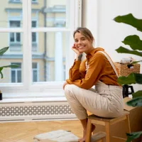 Femeie privind pe geamul apartamentului - Foto: Freepik