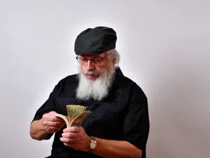 Un pensionar își numără pensia specială - Foto: Freepik