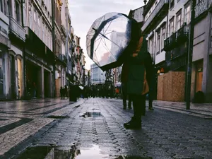 Persoană stând în mijlocul unei străzi pietonale, ferindu-se de ploaie cu o umbrelă - Foto: Pexels/Ali Müftüoğulları