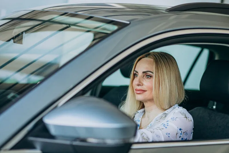 Femeie frumoasă r&acirc;z&acirc;nd, de la volanul unei maşini - Foto: Magnific.com/senivpetro