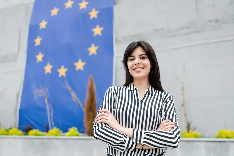 Portretul unei femei zâmbitoare cu steagul Uniunii Europene - Foto: Freepik (rol ilustrativ)