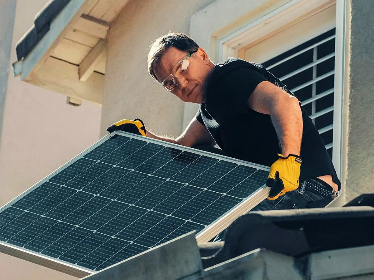 Bărbat montând un panou solar pe casă - Foto: Pexels/Kindel Media