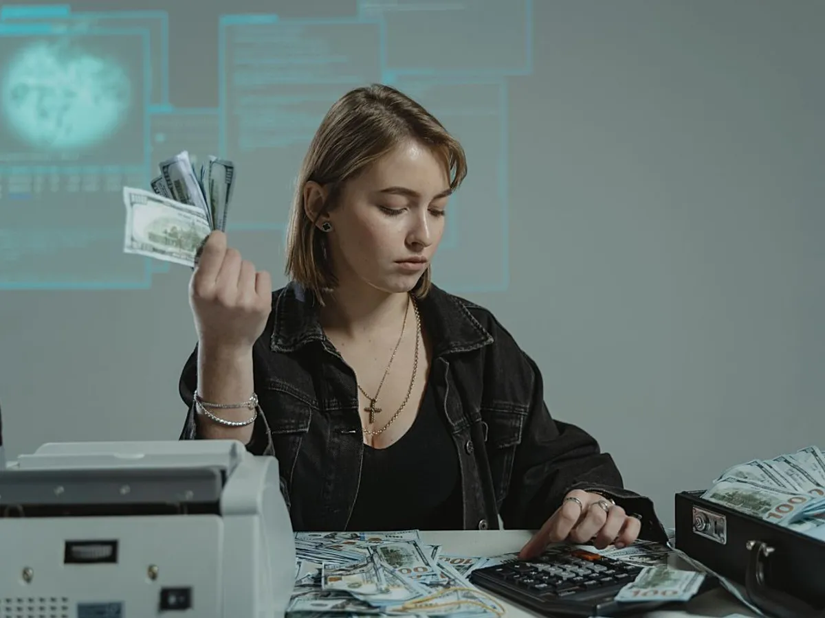 Femeie făcând calcule şi numărând bani, la birou - Foto: Pexels/Tima Miroshnichenko