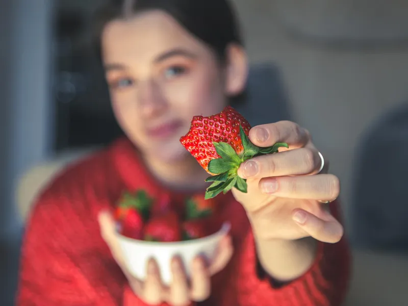 Femeie frumoasă care ține o căpșună în mână - Foto: Freepik