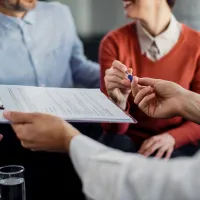 Consultant în asigurări dâ nd asiguratului pixul, pentru a semna contractul - Foto: Magnific.com/Drazen Zigic