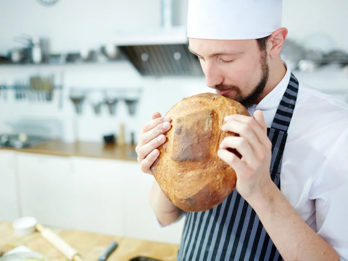 Bucătar care miroase o pâine - Foto: Freepik (Imagine cu rol ilustrativ)