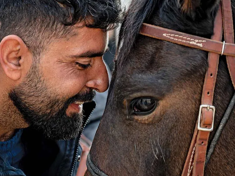 Yasser Haider, care s-a născut fără picioare, împărtășește un moment de tandrețe cu un cal, la centrul ecvestru al Fundației Springs of Hope din Shariya