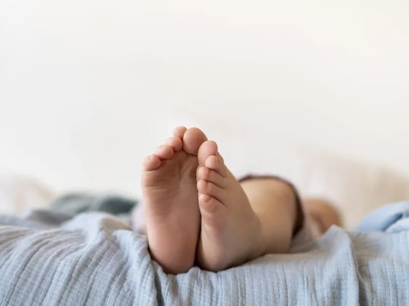 Plan apropiat cu picioare de bebeluş stând întins în pătuţul lui - Foto: Freepik/CC0