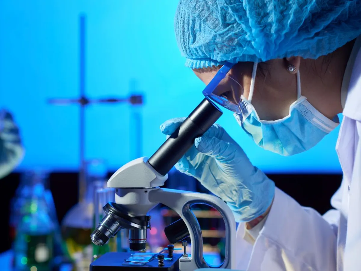 Cercetătoare analizând o probă la microscop - Foto: Magnific.com/pressfoto