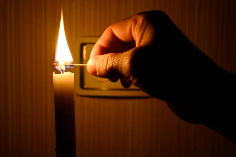 Persoană care aprinde o lumânare pe întuneric - Foto: Freepik (rol ilustriv)