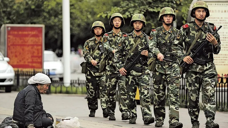 O bătrână musulmană uigură, în capitala regională Urumki, cerșește, în timp ce poliția paramilitară chineză patrulează