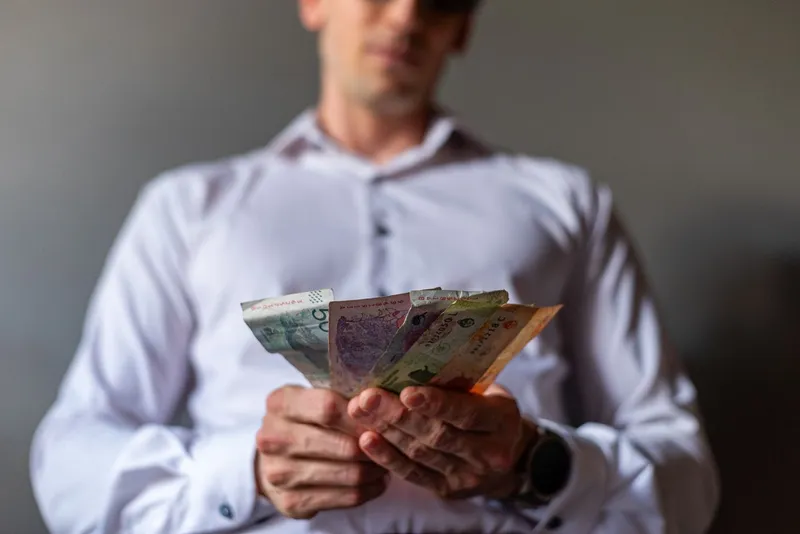 Bărbat care ține bancnote &icirc;n m&acirc;nă - Foto: Pexels (Imagine cu rol ilustrativ)