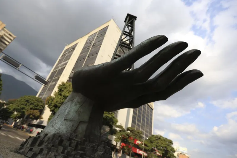 O sculptură a unei m&acirc;ini care ține o platformă de foraj petrolier, &icirc;n faţa sediului central al PDVSA, din Caracas - Foto: Profiedia Images