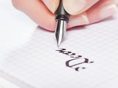 O persoană scrie un cuvânt cu stiloul - Foto: Profimedia (cu rol ilustrativ)