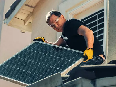 Bărbat montând un panou solar pe casă - Foto: Pexels/Kindel Media