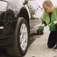 Bărbat care inspectează roțile unei mașini - Foto: Freepik