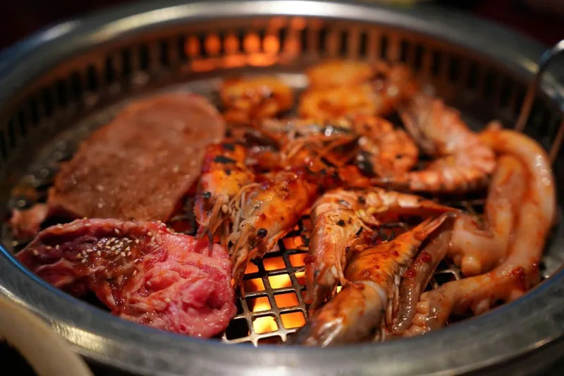 Churrasco, tradiţionalul grătar brazilian din carne de vită, este gata de m&acirc;ncat. Prin grătar se văd nerăbdătoare să fie consumate şi nişte languste prăjite - Foto: Profimedia Images