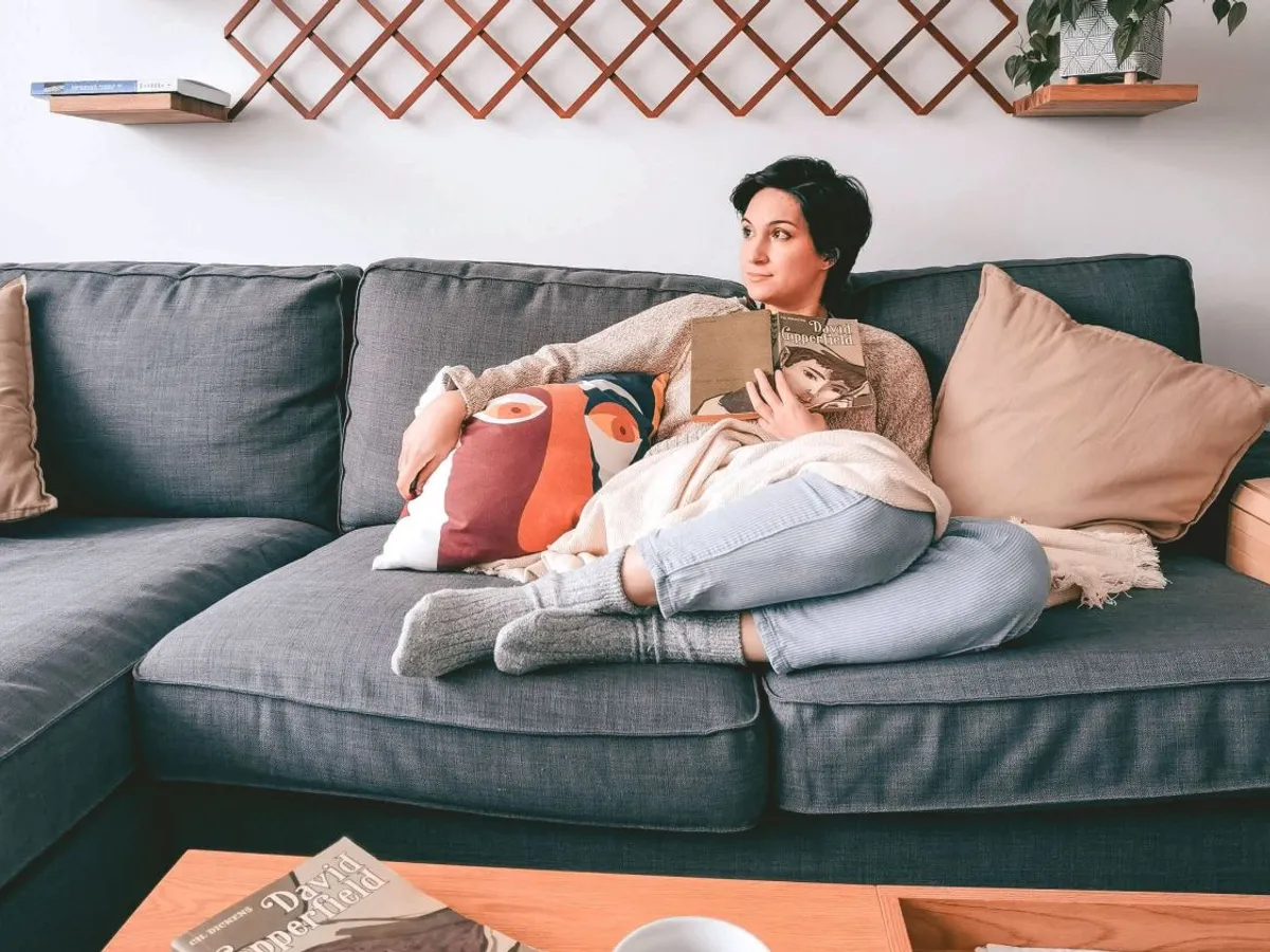 Femeie relaxată, stând pe sofa, în caamera ei de zi - Foto: Pexels/Nicoleta S.