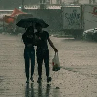 Tânăr cuplu mergând prin ploaie, sub umbrelă - Foto: Pexels/Nikita Korchagin