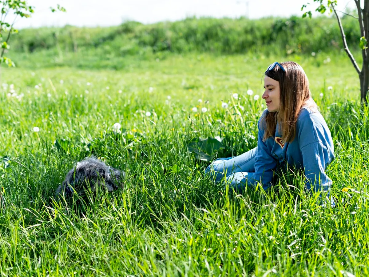 Femeie care stă în iarbă - Foto: Magnigic.com (Imagine cu rol ilustrativ)