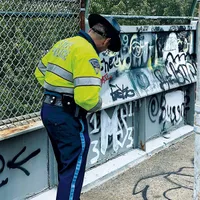 Polițistul Millet examinează grafitti-ul bandei, în aproprierea orașului Boston