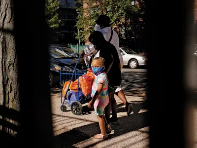DUREREA FOAMEI O femeie și doi copii părăsesc o bancă de alimente din Brooklyn, New York. TEB-ul de vară va oferi familiilor cu venituri mici 120 de dolari de copil pentru cumpărături