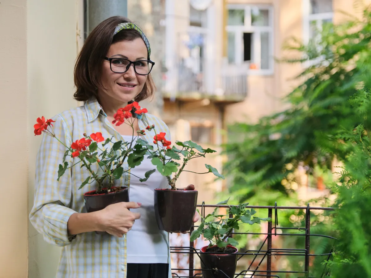 Femeie cu flori în balcon - Foto: Magnific.com (Imagine cu rol ilustrativ)