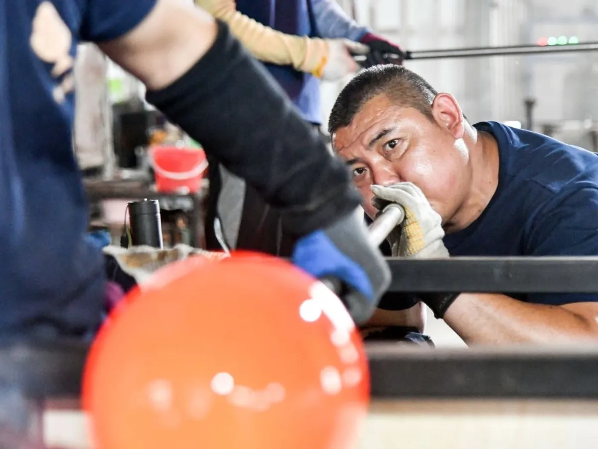 Un meșter chinez realizează o operă de artă cu glazură colorată, într-un atelier - Foto: Profimedia Images
