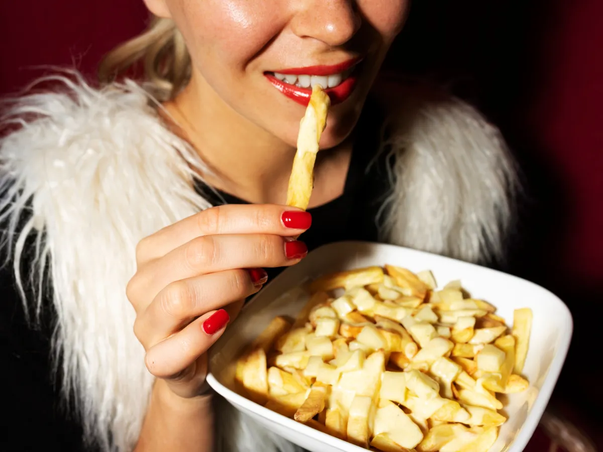 Femeie care mănâncă cartofi prăjiți - Foto: Freepik (Imagine cu rol ilustrativ)