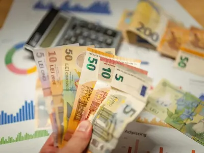 Un bărbat ţine în mână un evantai de bancnote euro - Foto: Pexels/Jakub Zerdzicki