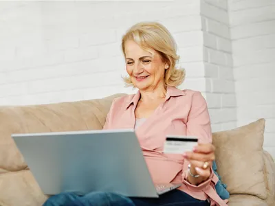 Pensionară la pensie cu cardul în mână - Foto: Freepik