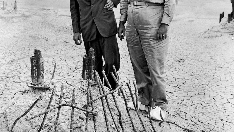 Generalul maior Leslie Groves, în dreapta, și Oppenheimer privesc baza turnului de oțel de care a atârnat bomba în timpul testului de lângă Alamogordo, New Mexico, în iulie 1945