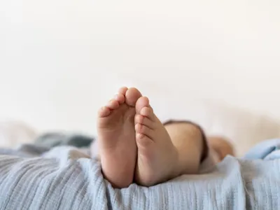 Plan apropiat cu picioare de bebeluş stând întins în pătuţul lui - Foto: Freepik/CC0