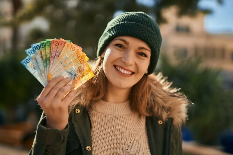 Femeie blondă veselă, cu un evantai de bancnote euro &icirc;n m&acirc;nă - Foto: Magnific.com/krakenimages.com