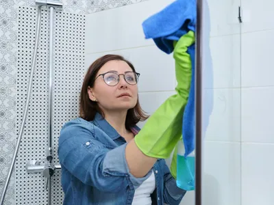 Femeie care șterge cabina de duș - Foto: Magnific.com (Imagine cu rol ilustrativ)