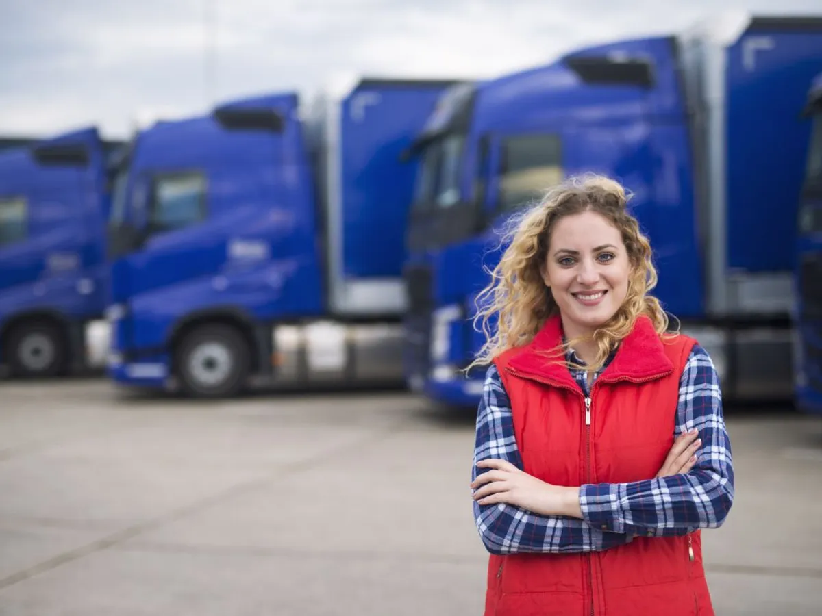 Şoferiţă de camion pozând în faţa vehiculelor - Foto: Magnific.com/aleksandarlittlewolf