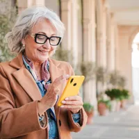 Pensionară verificând pe telefon dacă i-a intrat pensia - Foto: Freepik