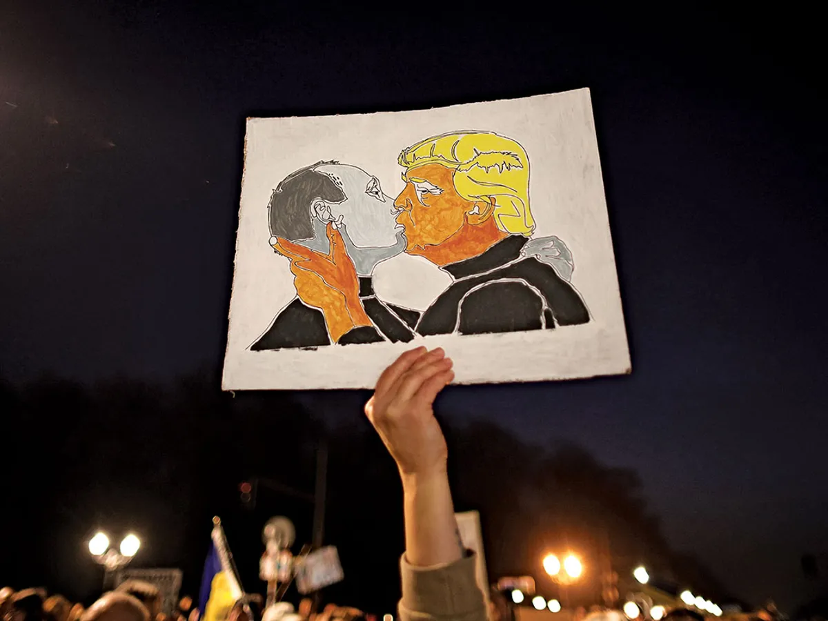 ARTA PROTESTULUI  Un manifestant ține un banner care înfățișează o ilustrație cu Putin și Trump sărutându-se în timpul unei manifestații de sprijin pentru Ucraina, pe 9 martie, la Berlin, Germania.