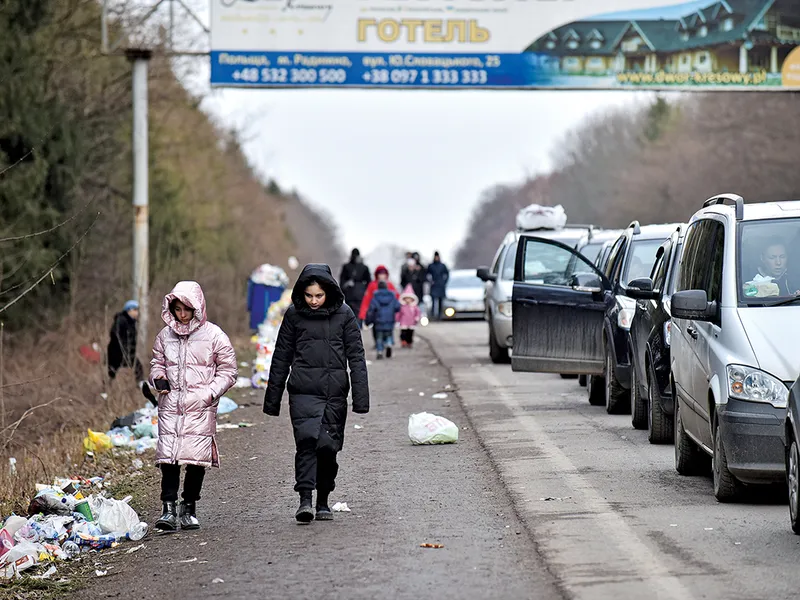 Copiii merg alături de un șir de mașini lung de 19 kilometri care așteaptă să treacă granița dintre Ucraina și Polonia