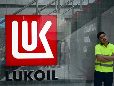 Un bărbat stă în faţa logo-ului Lukoil, la  Abu Dhabi International Petroleum Exhibition & Conference - Foto: Profimedia Images