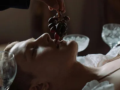 Femeie întinsă pe spate pregătindu-se să mănânce un strugure - Foto: Pexels/cottonbro studio