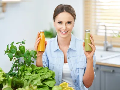Femeie care ține în mână două sticle de suc natural - Foto: Freepik (imagine cu rol ilustrativ)