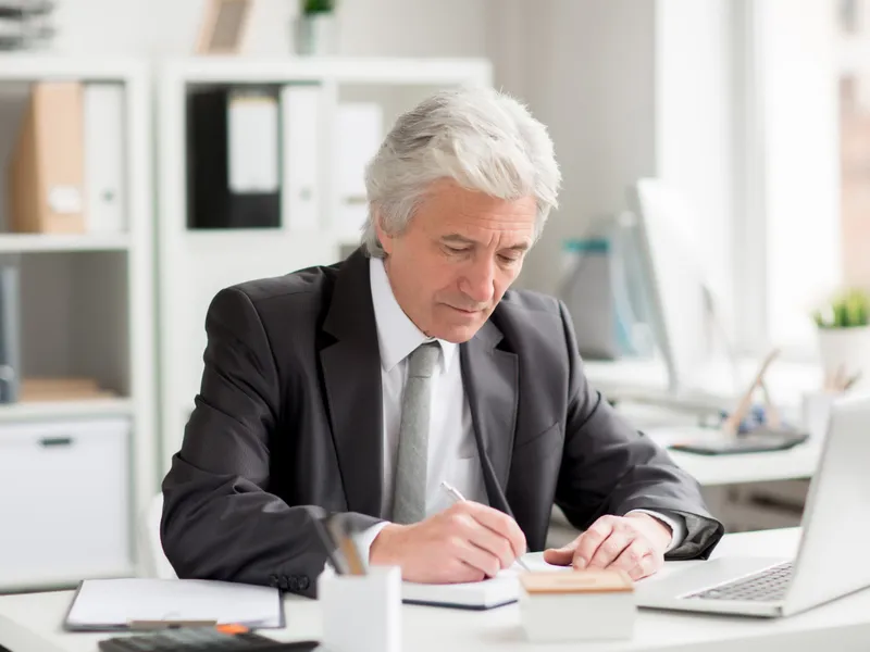 Foto: Pensionar care completează contestarea unei decizii de recalculare conform noii lei a pensiilor (Freepik )